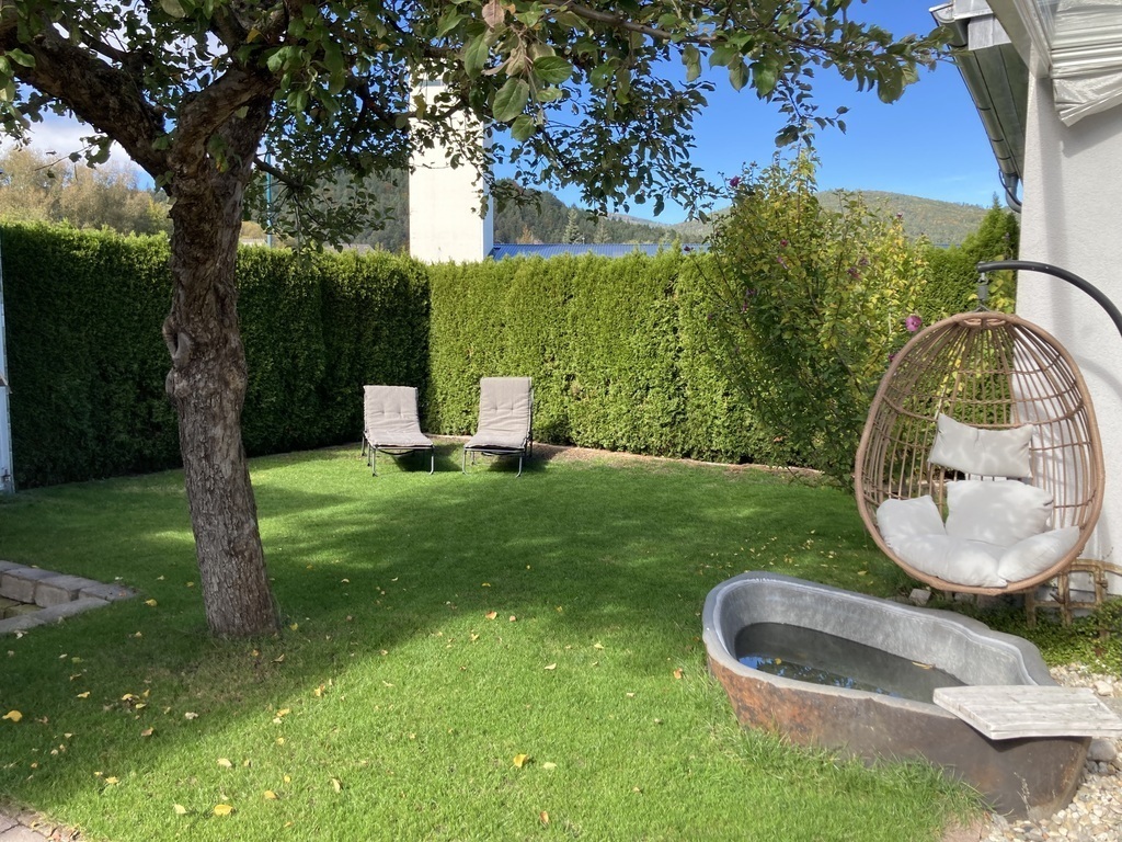 Garten mit zwei Sonnenliegen, Hängesessel, Badewanne aus Stein
