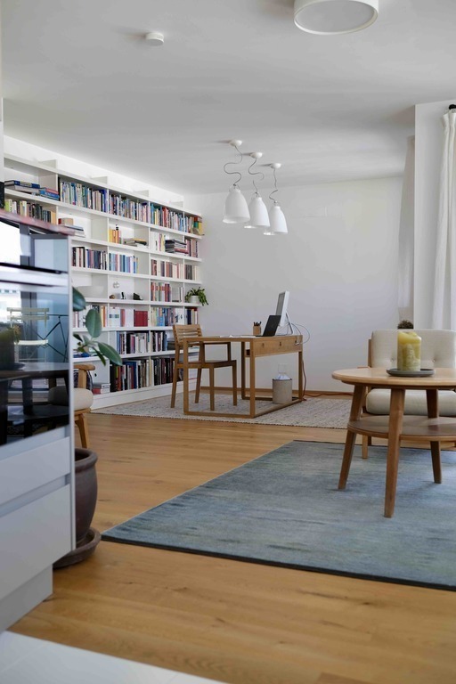 Living area with desk and bookshelf, door to balcony to the right
