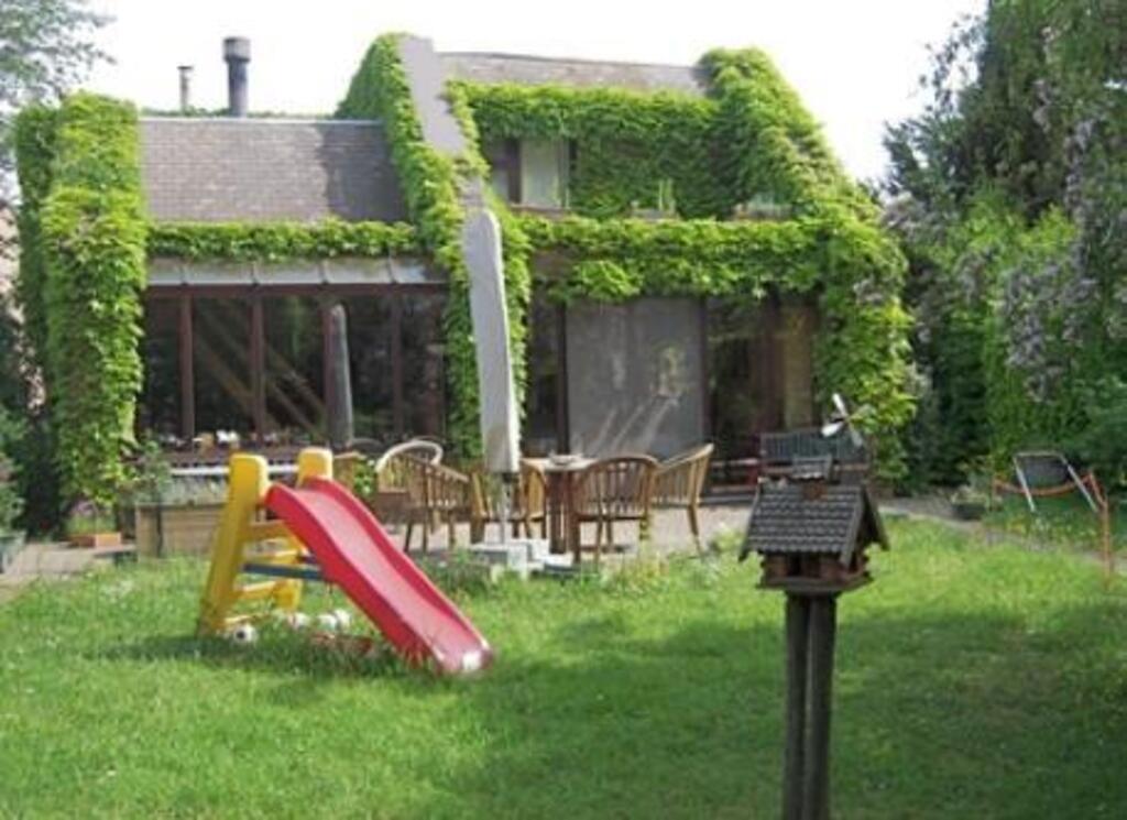 house seen from the garden with terrace table and slide