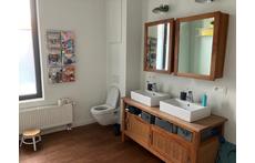Large bathroom with bath, shower, toilet and two sinks on the first floor.