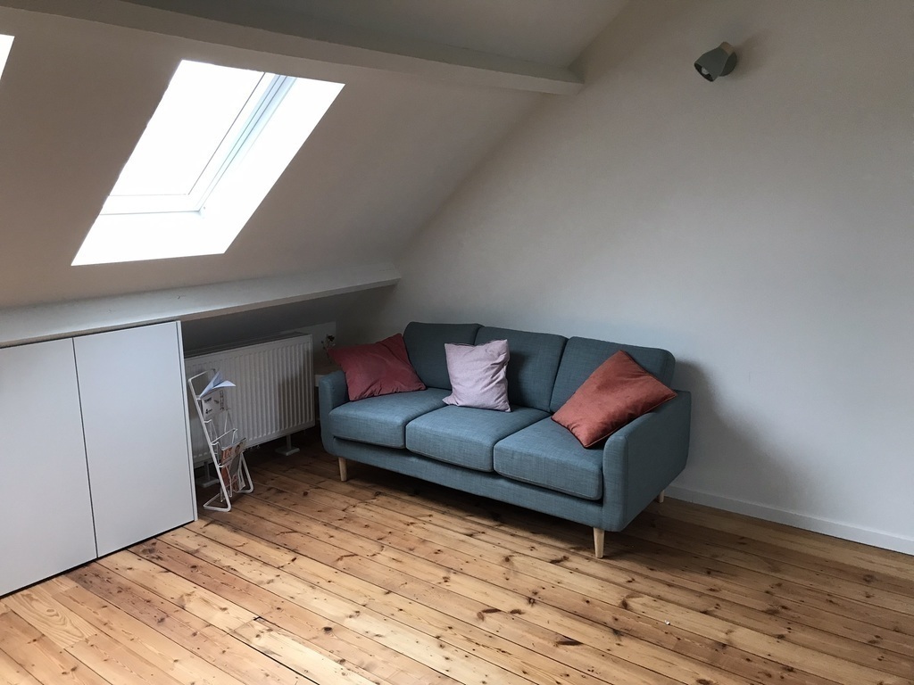 Spacious, bright attic with desk and sofa on the third floor.