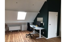 Spacious, bright attic with desk and sofa on the third floor.