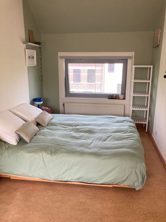 Queen size bed in the corner of the open space.