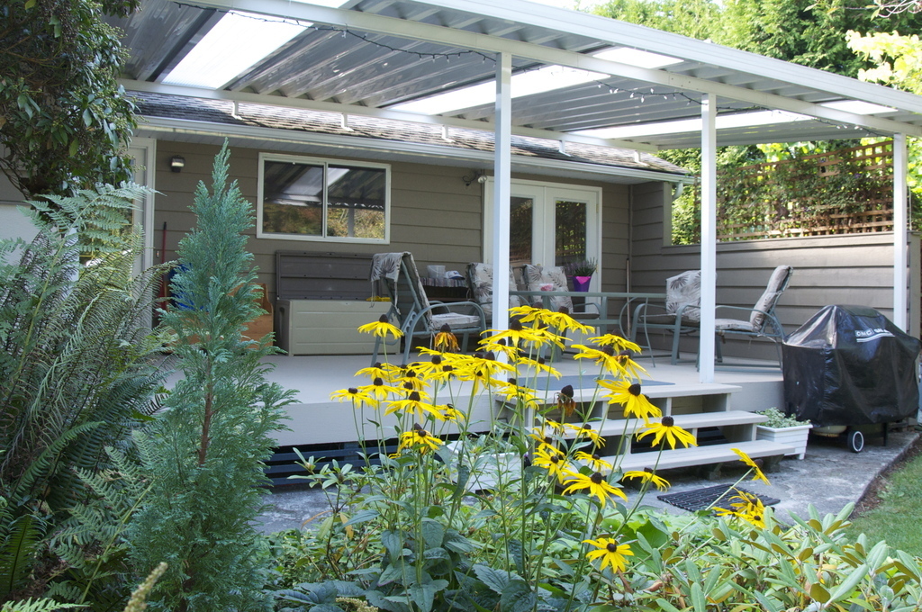 Roof-covered patio, with an outdoor table and chairs, facing the backyard