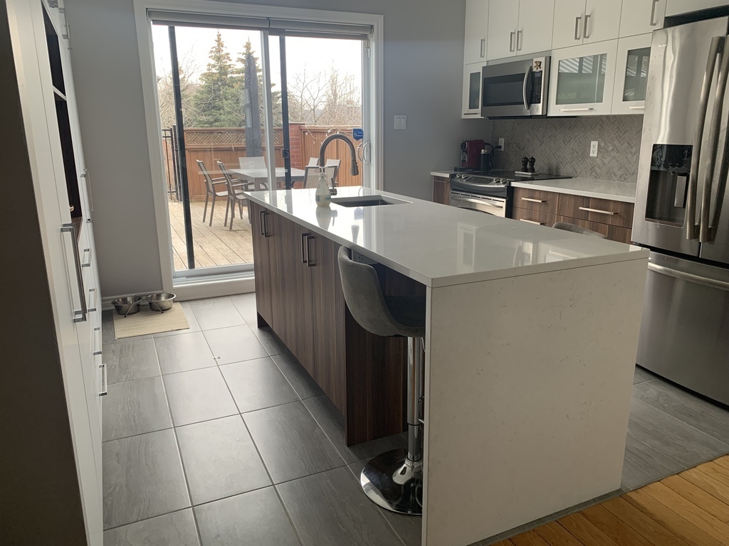 Cuisine moderne et fonctionnelle avec micro-ondés, cuisinière, lave-vaisselle et frigo récents.