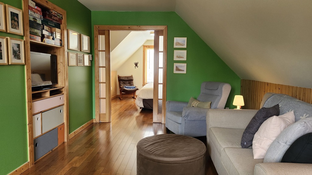 Salon-télé à l'étage avec divan-lit. Au fond, face au lac, la chambre de maîtres.