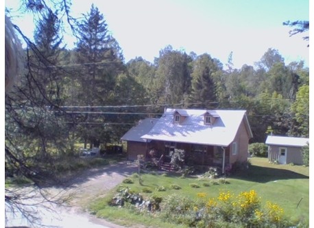 Vue d'ensemble d'une petite maison canadienne et de terrain, paisible et enchanteur.