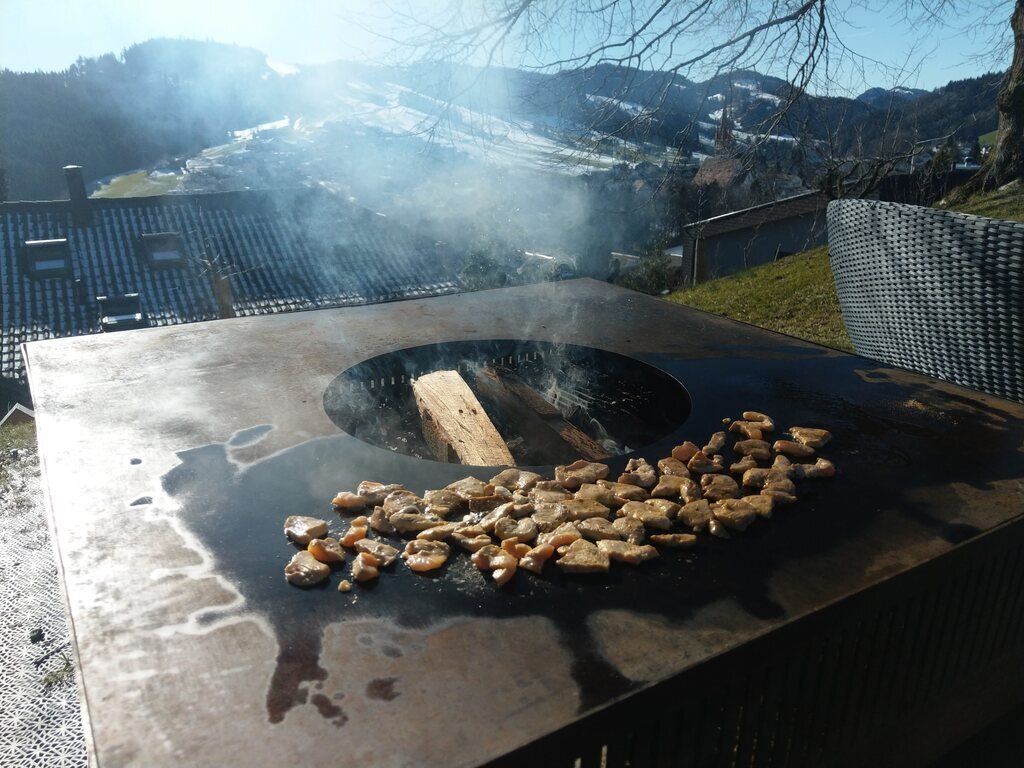 Gartensitzplatz mit Lounge und Grillstelle zuoberst im Garten