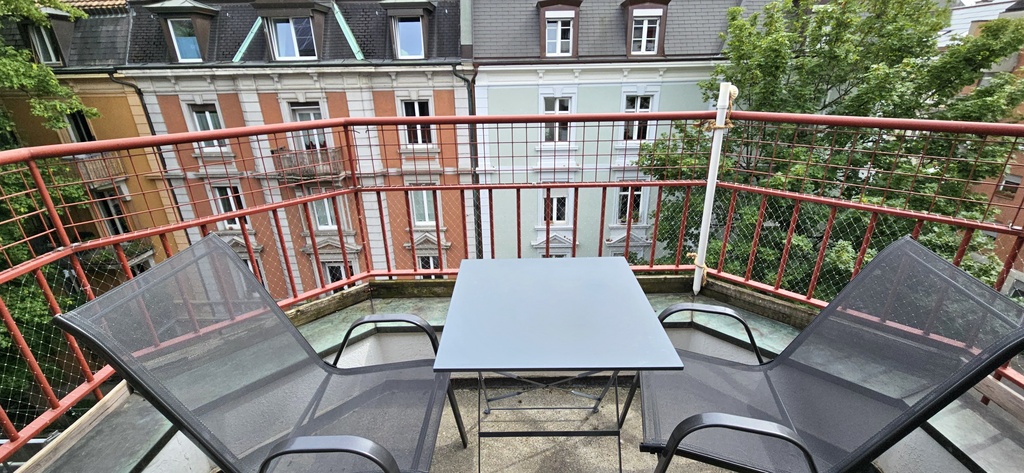 Balcony over looking a tree lined street and river to the left