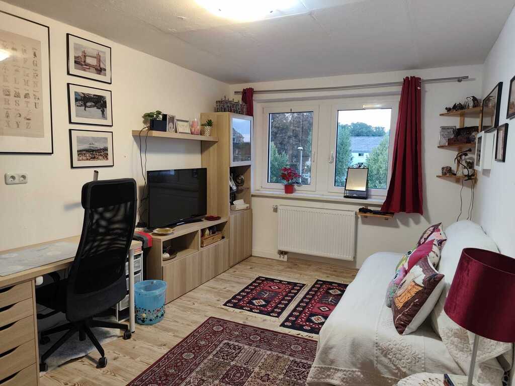 There is a single bed in the living room, but there is still space to add another bed. There are also two desks.