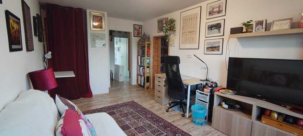 There is a single bed in the living room, but there is still space to add another bed. There are also two desks.