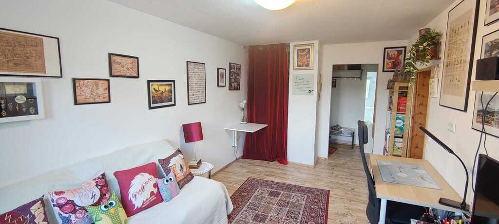 There is a single bed in the living room, but there is still space to add another bed. There are also two desks.