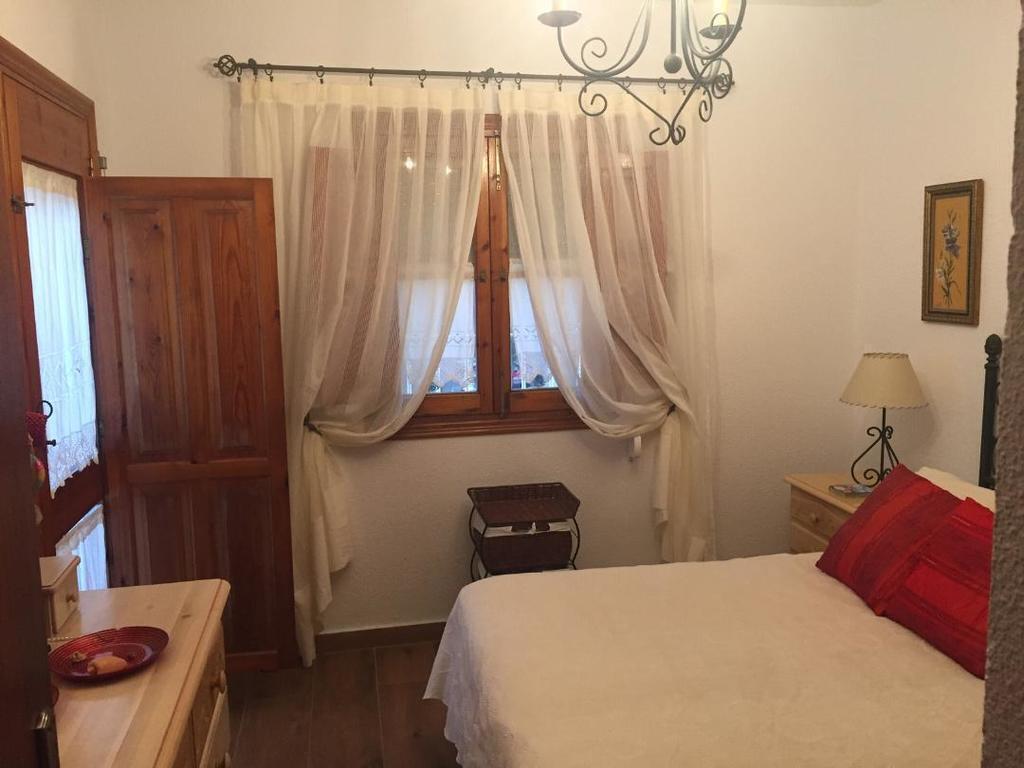 Habitación principal con cama de matrimonio, armario empotrado, cómoda y balcón.