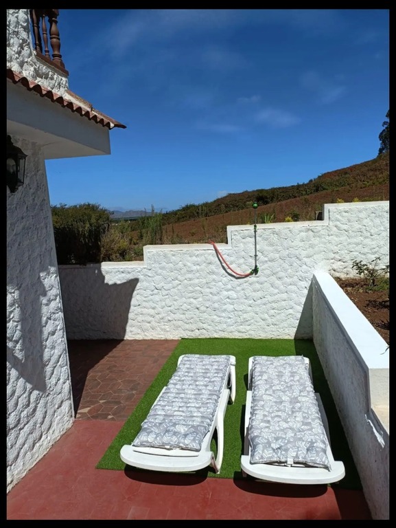 Zona de tumbonas y ducha en la terraza lateral de la vivienda