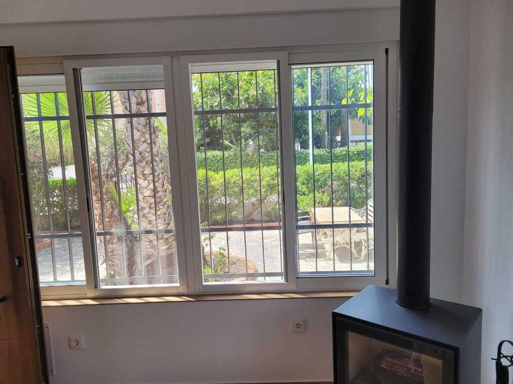 Ventanal del Salón con vistas al jardín y estufa de leña del salón