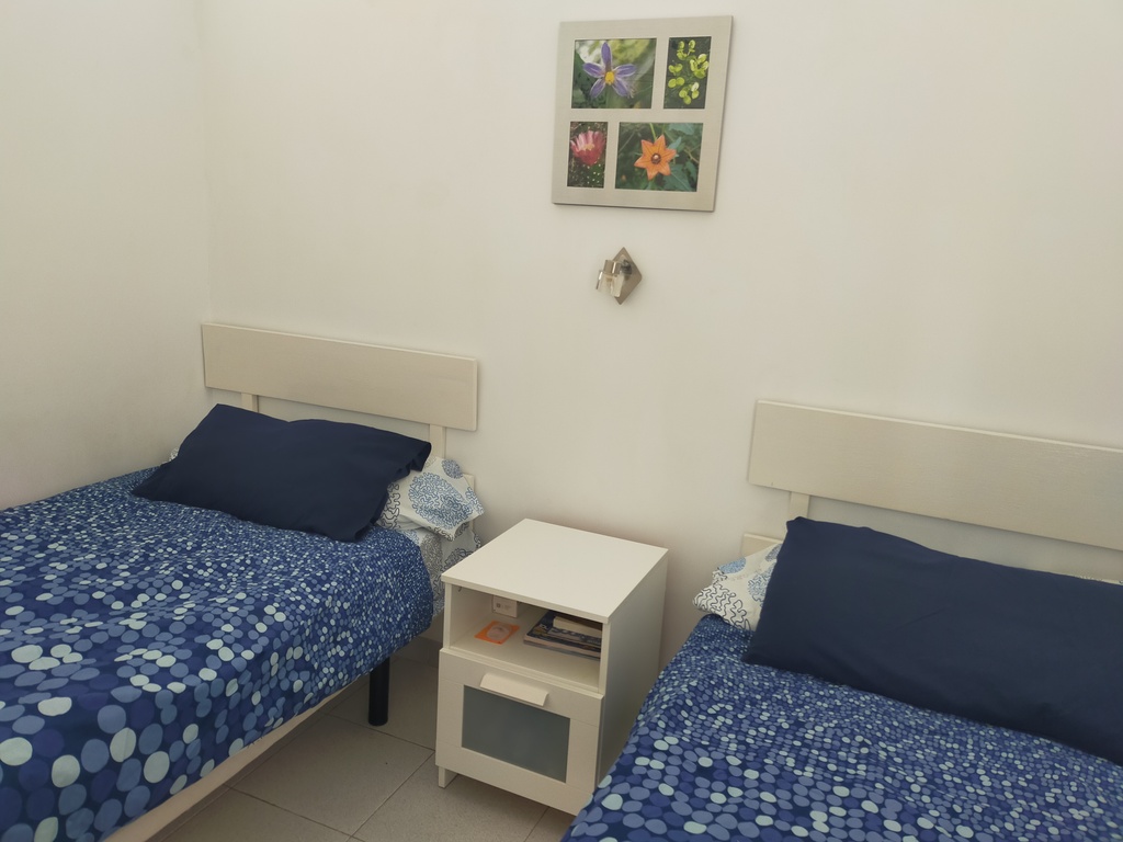Dormitorio con 2 camas individuales, armario grande y mesa de noche. 