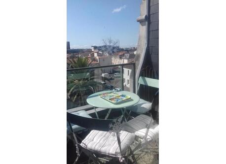 Balcon avec vue sur palmier et toits de La Rochelle