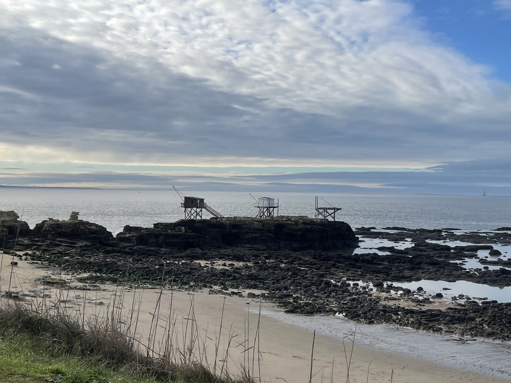 Les carrelets sur la côte et au fond, le phare de Cordouan 