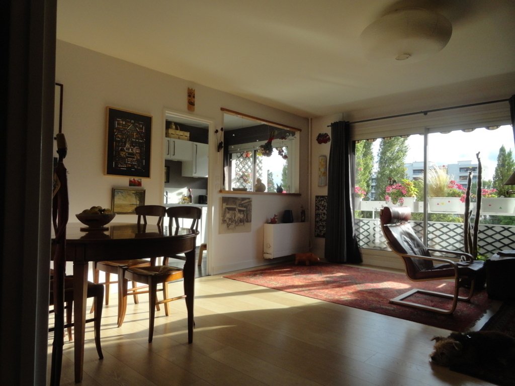 Living room facing west overlooking the wooded park, seen from the entrance. kitchen in the background.
