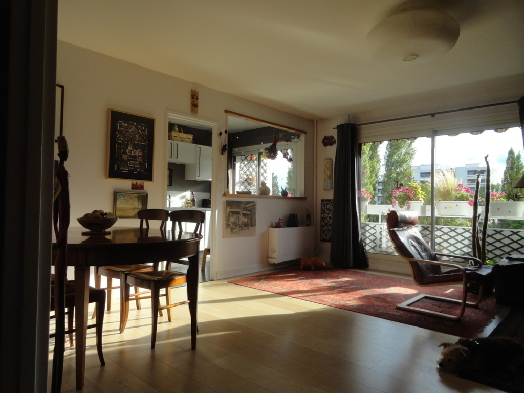 Living room facing west overlooking the wooded park, seen from the entrance. kitchen in the background.