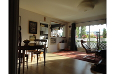 Living room facing west overlooking the wooded park, seen from the entrance. kitchen in the background.