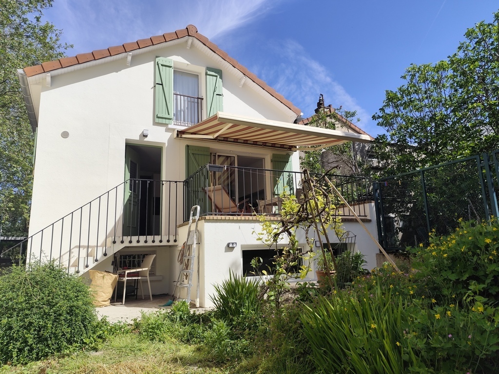 L'arrière de la maison vu du jardin : l'entrée, la terrasse, tout en bas un bureau avec un accès direct au jardin, tout en ha...