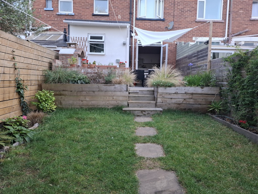 Back garden in summer with shade sail.