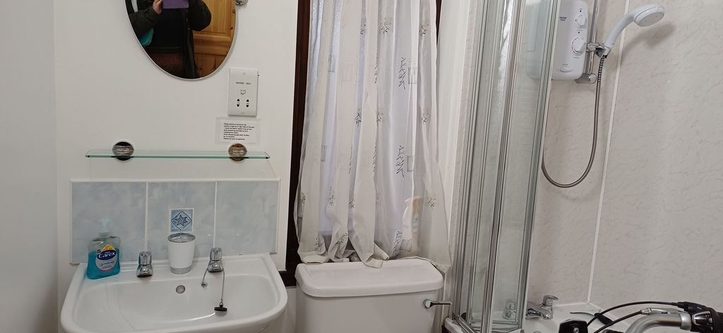 Large bathroom with shower over bath and folding screen. 