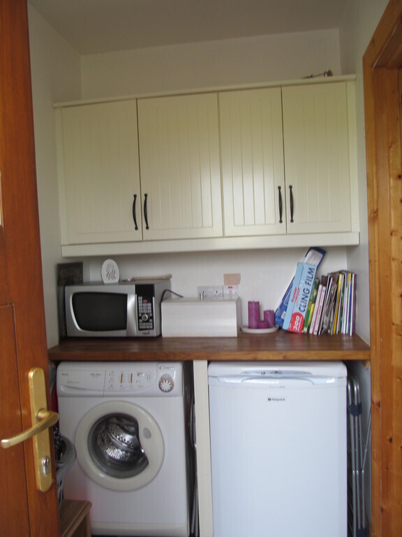Utility room wit washer dryer, microwave and small freezer.