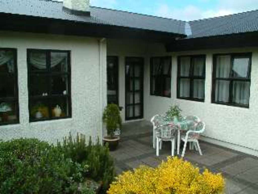 The porch behind the house where you can sit and enjoy a nice lunch. It's completely enclosed by hedge or fence. 