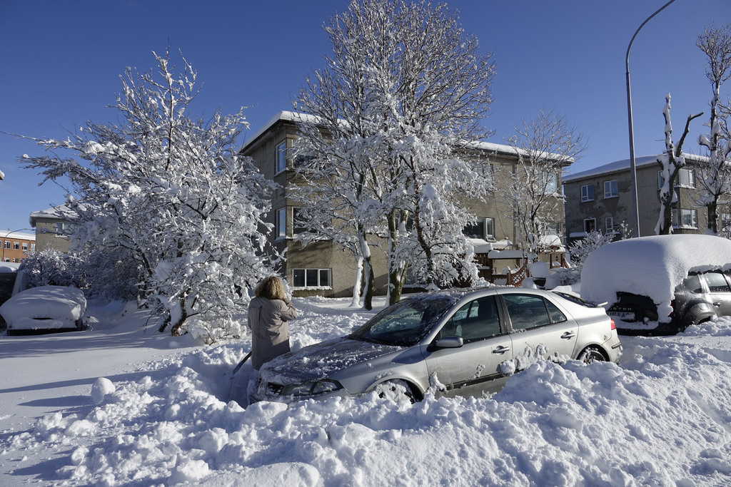 Snow like that is not common in Reykjavík anymore. Our home and Signy showelling snow from our car at the time.