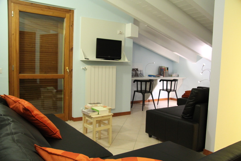 sitting area with TV, 2 sofa , wardrobe, bureau and door to the balcon