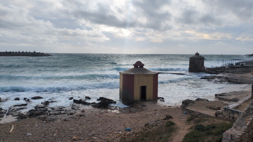 Leuca d’inverno: mare mosso, cielo intenso e antiche cabine sul litorale, tra luce, vento e Mediterraneo.