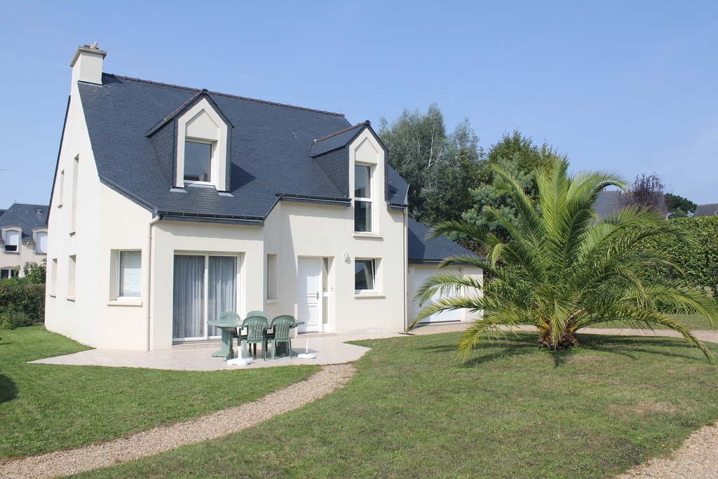 Front view of the house, oriented to south. Garden around, and garage on the right.