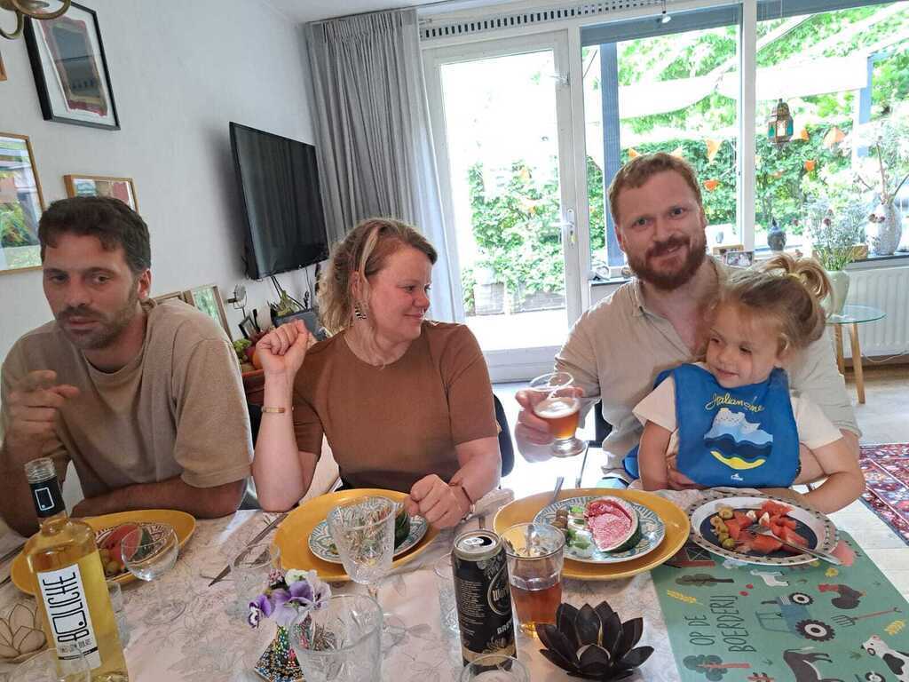 Etentje in huiskamer met gezin op bezoek