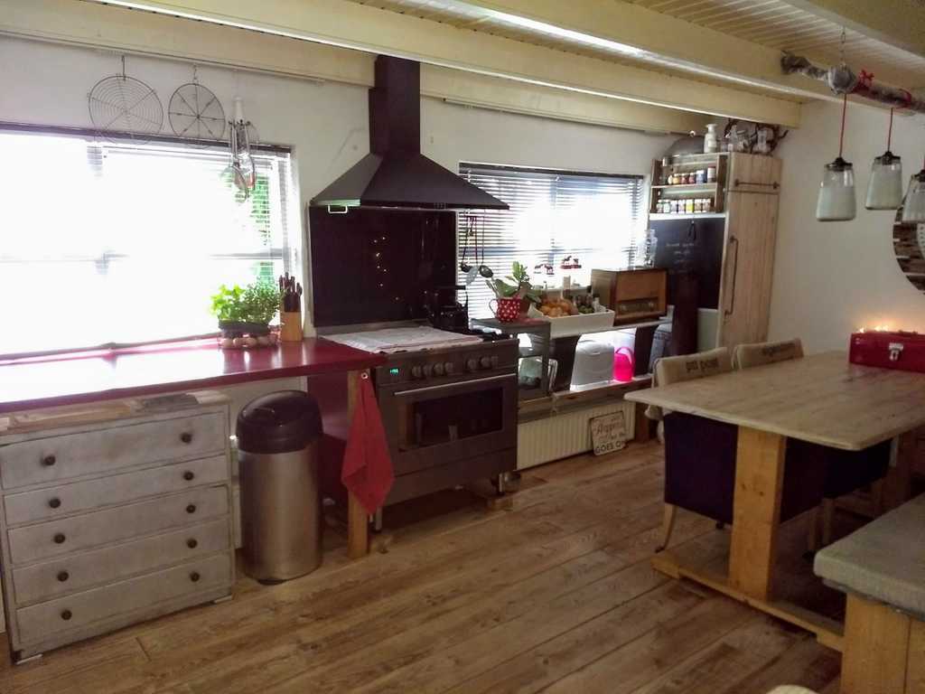 Keuken met zespits gasfornuis en uitzicht op de tuin.