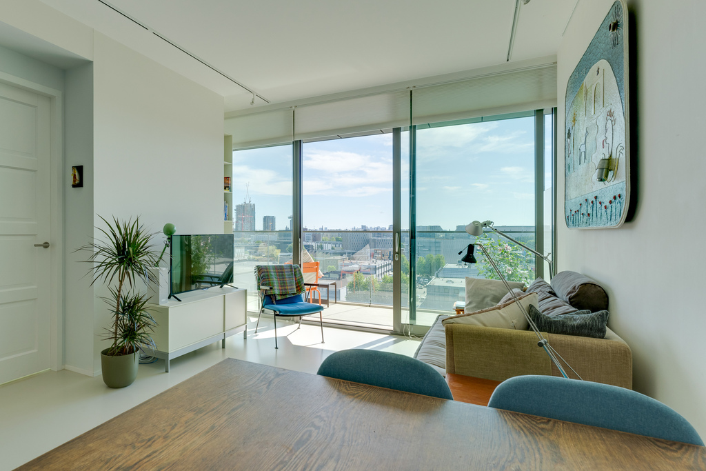 The living area opening up to the balcony, with view over the water of IJ river and the city of Amsterdam.