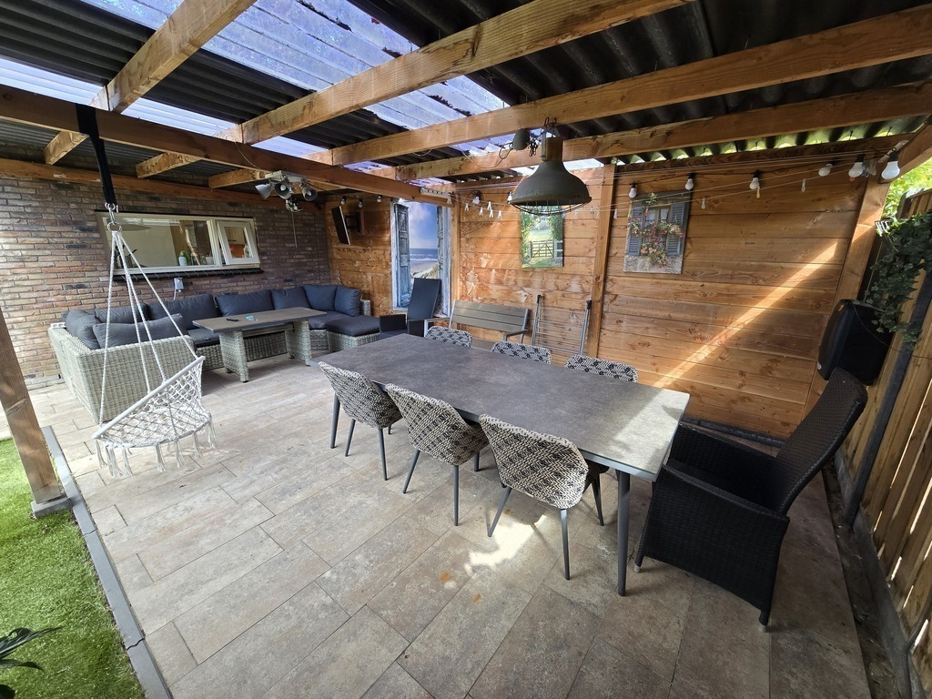 Veranda met eettafel en loungebank en TV
