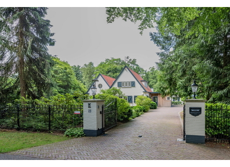 De voorkant van het huis, het terrein is met een ijzeren hek begrensd. 
