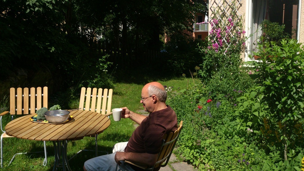 Jan drinking coffe at one of the tables in the garden.