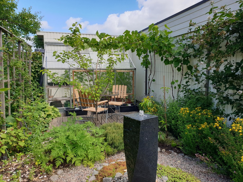 The small seating area outside the greenhouse. Waterstone, berries and herbs.