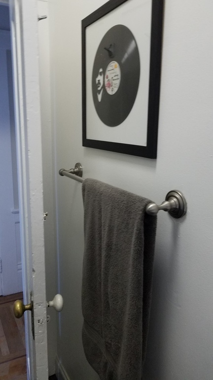 Bathroom towel rack with a Prince album above.