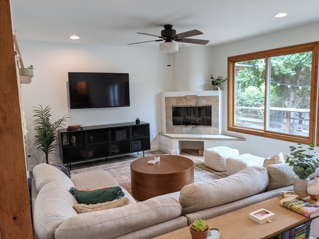 Third living space with TV, gaming console (PS4), and fireplace. Views of front fenced yard. 