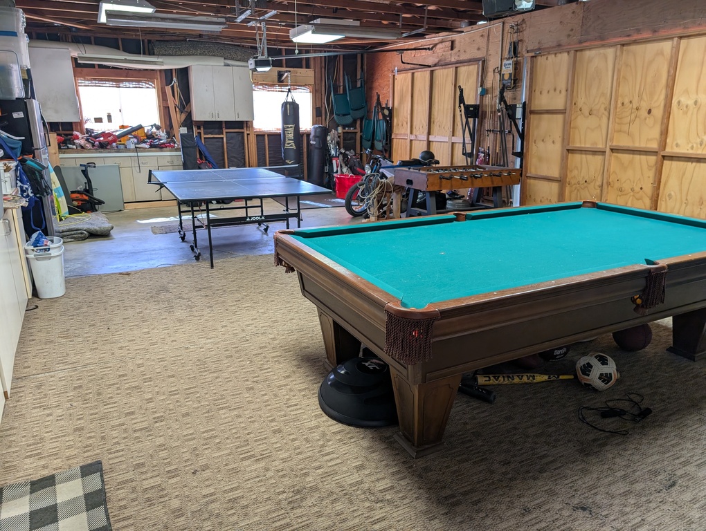 Garage (game room) with billiards, ping pong table, foosball table, exercise equipment including a punching bag. 