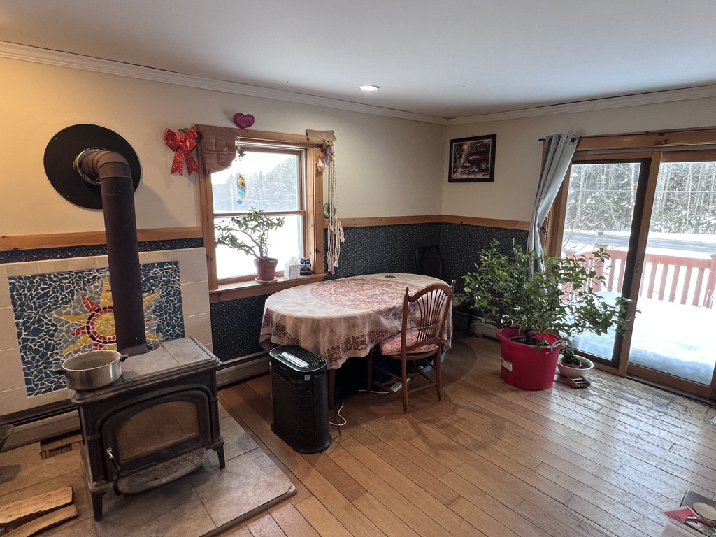 Living Room with dinner table and wood stove.  Slider door goes to deck.  