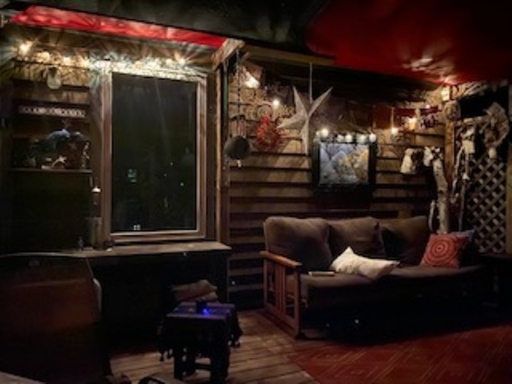 Our cozy back deck at night.  Couch, table & chairs, hot tub.  Small grassy area. 