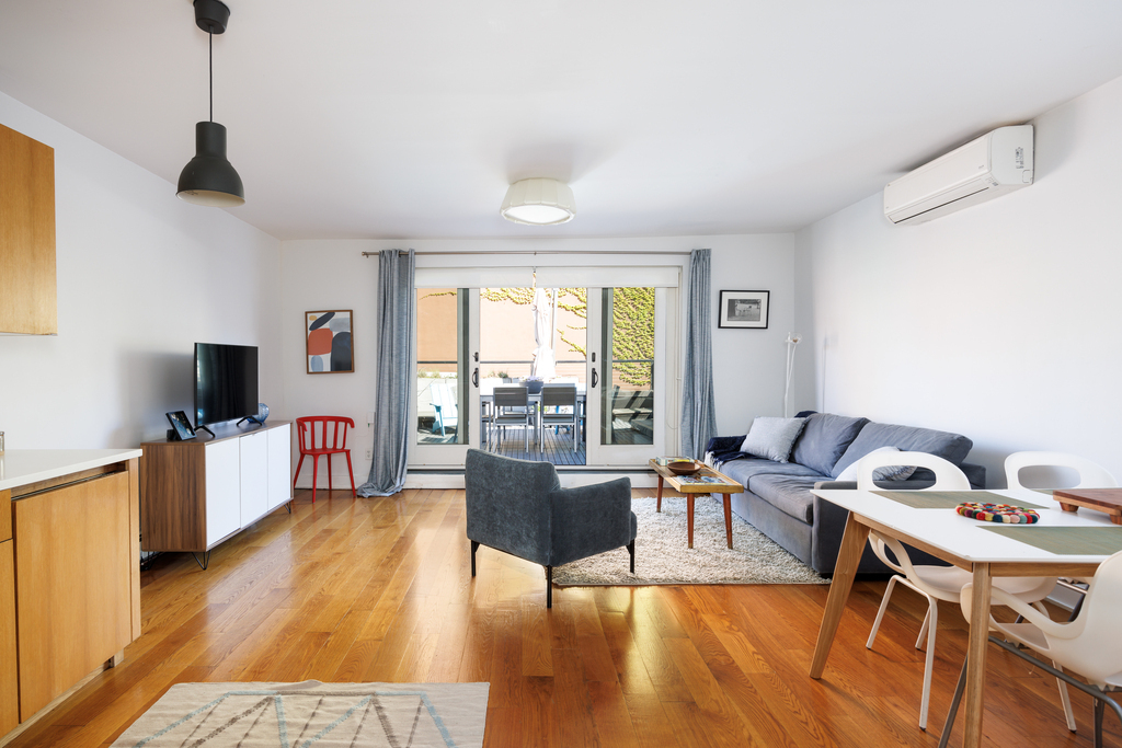 The living room is sunny + opens to private deck