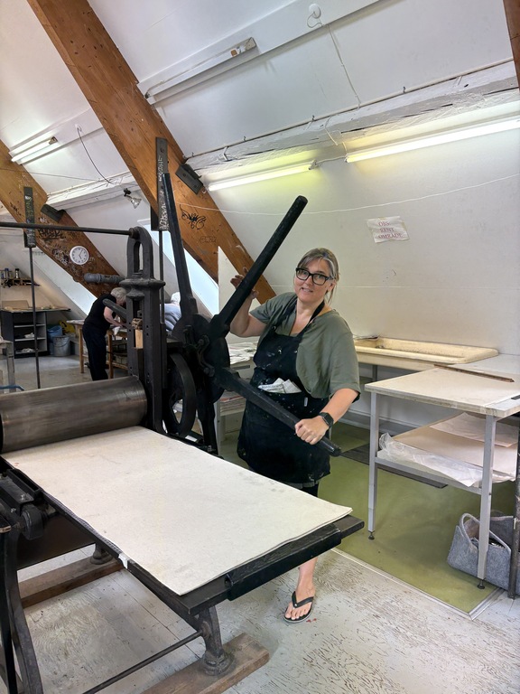 Pernille working a very old and very big printning press