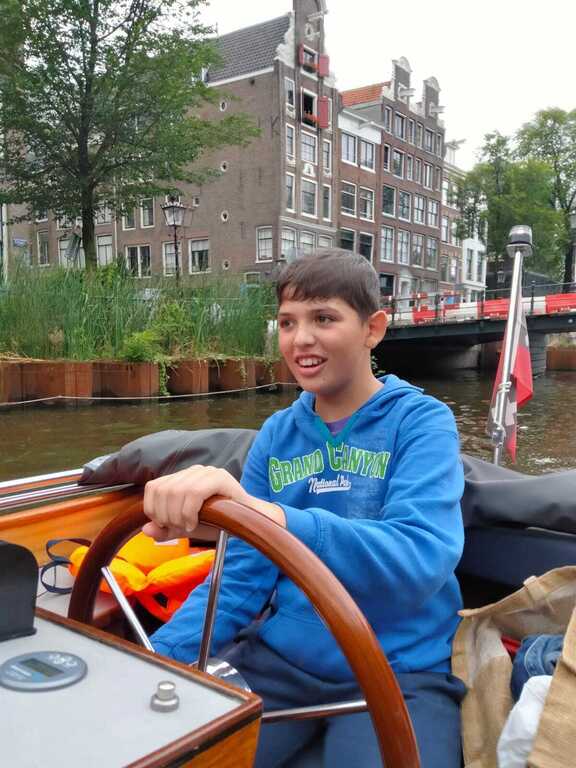 Carlo tries driving a boat in Amsterdam, our first exchange August 2024